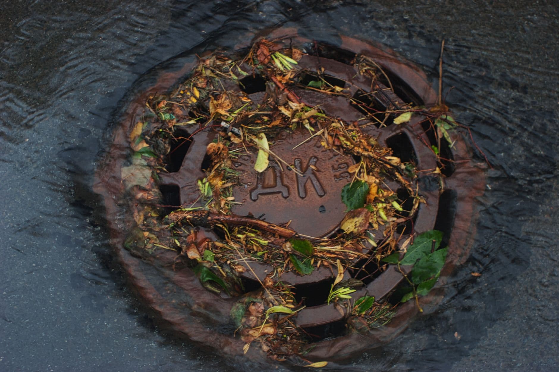 Image illustrating: Municipal workers clearing a wet street drain after flooding in Aiseau-Presles (editorial)