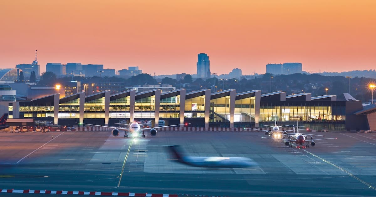 Passengers waiting at a Belgian travel agency or airport departures board during flight disruption
